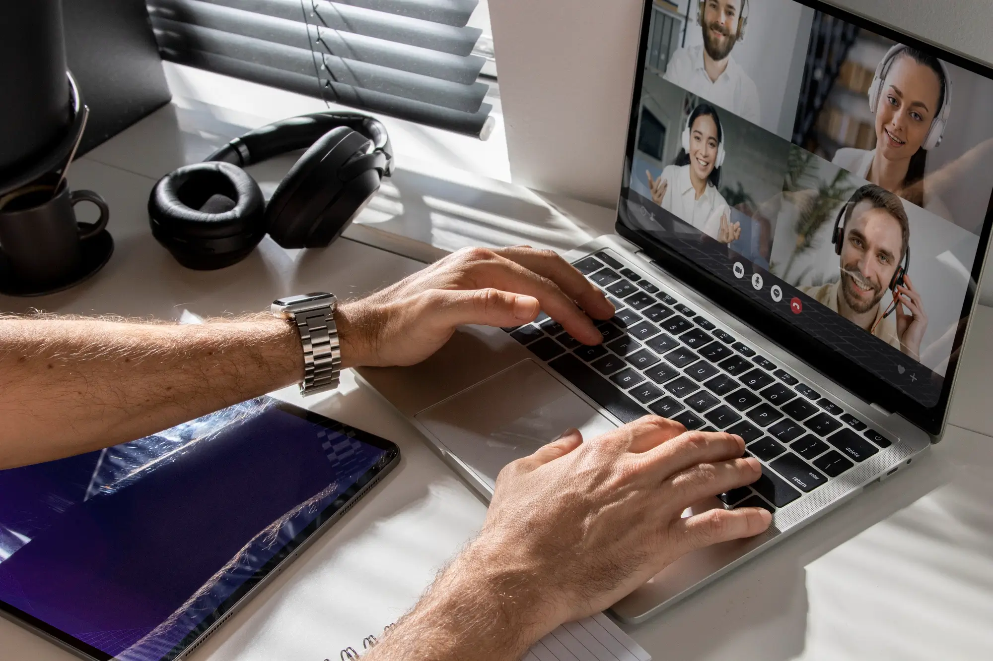 Hands placed on laptop, online meeting with 4 individuals on screen