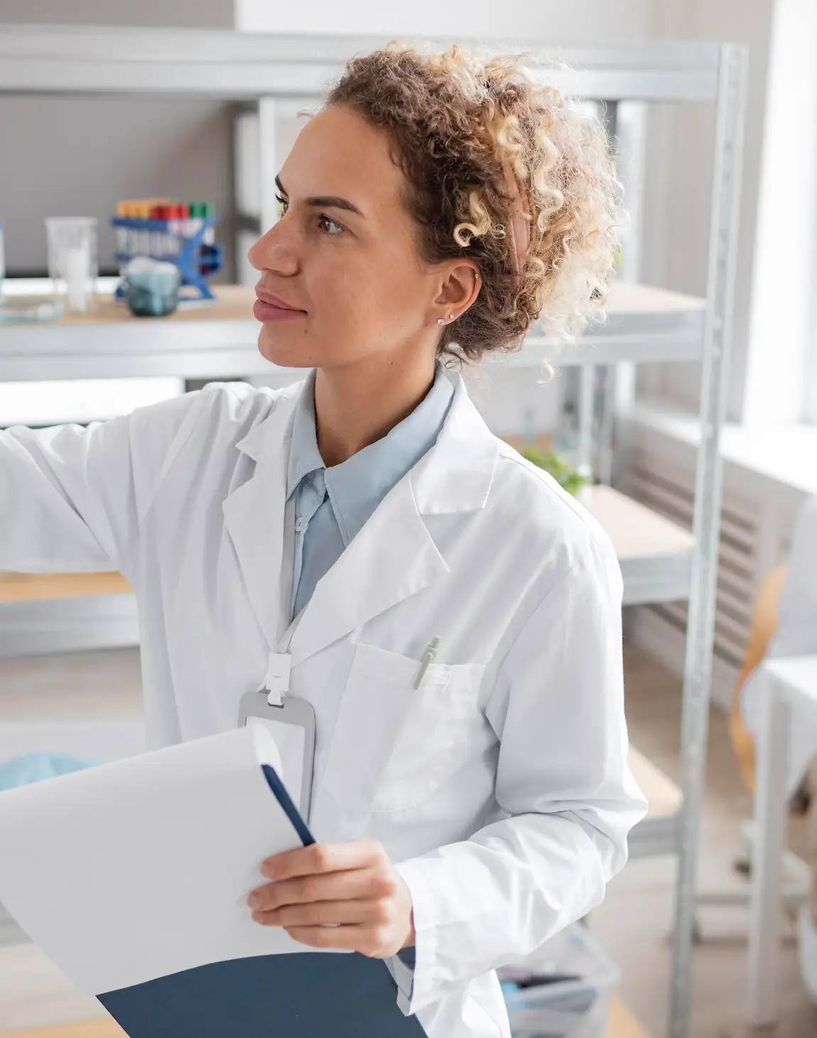 Medical student in white coat, holding notepad, writing on board
