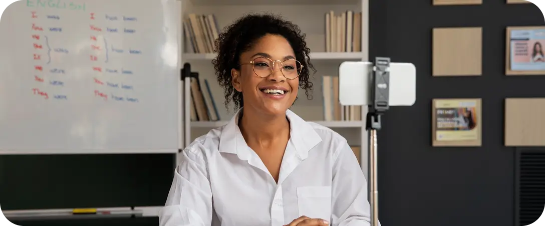 Student sat at desk looking smiling into video camera during online class